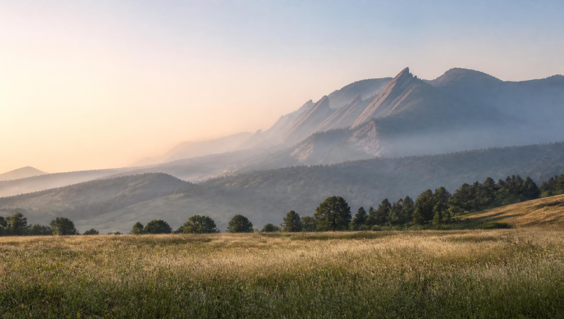 Morning light and low mist over the Flatirons above Boulder, Colorado, with an open meadow in the foreground